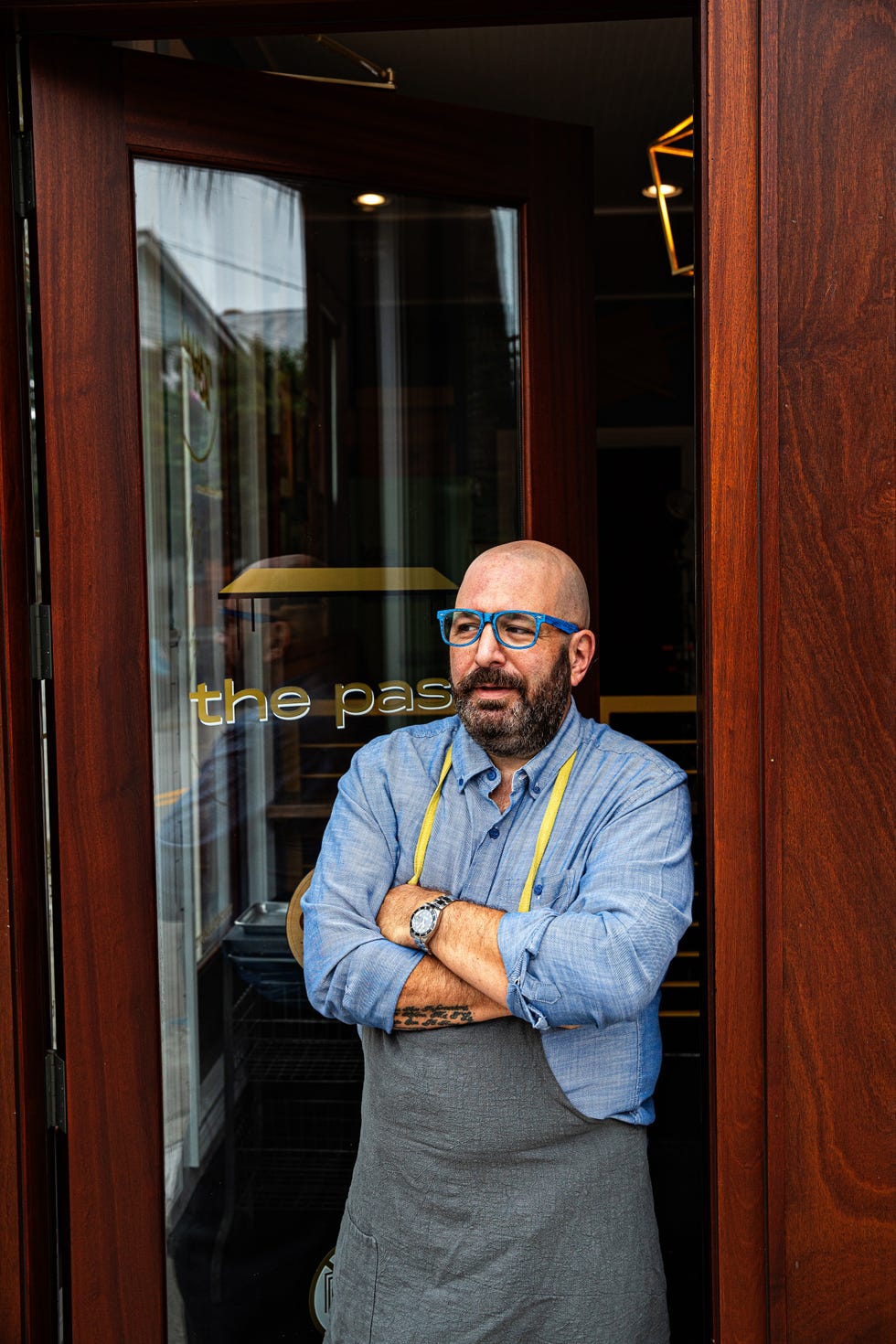 a person standing in front of a restaurant entrance arms crossed