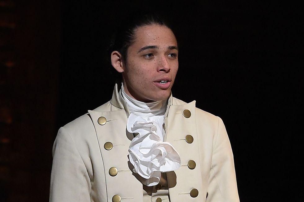 anthony ramos wearing a white dresscoat costume while performing on a stage