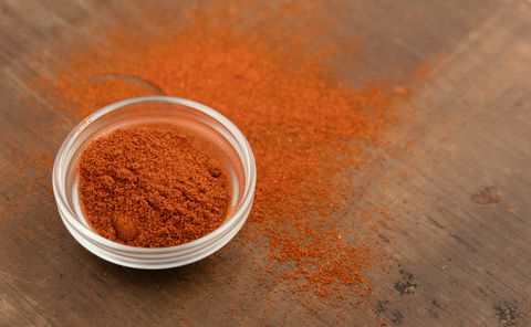 red pepper or powdered cayenne pepper in little glass bowl wooden board high point of view