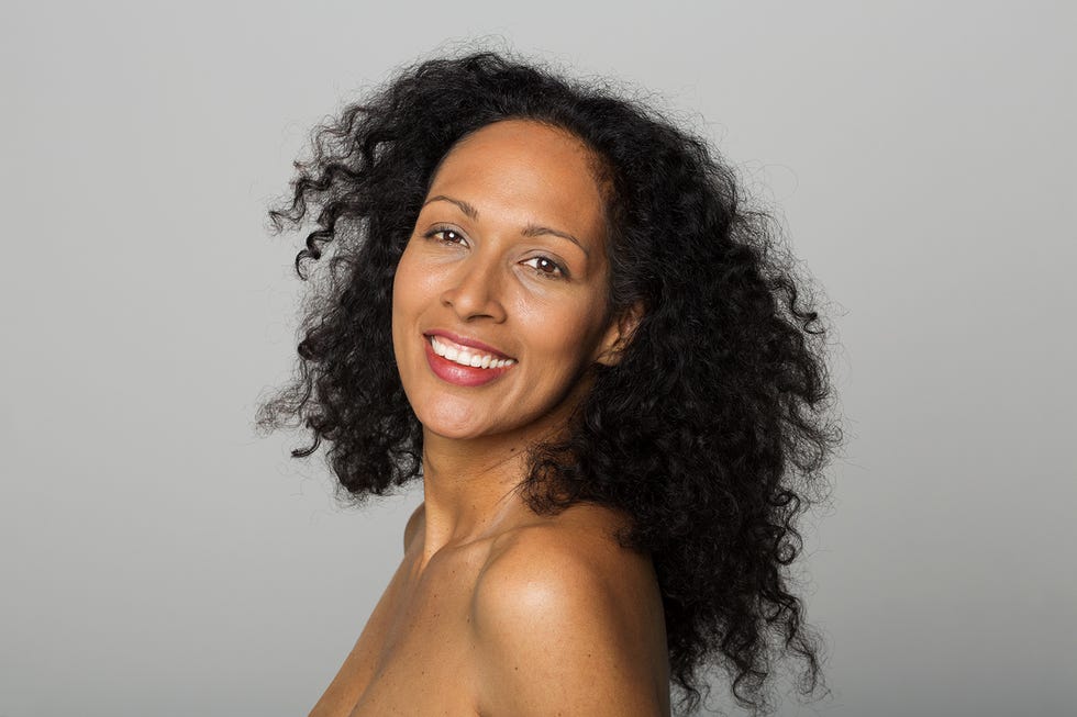 portrait of smiling mid adult woman standing against grey background
