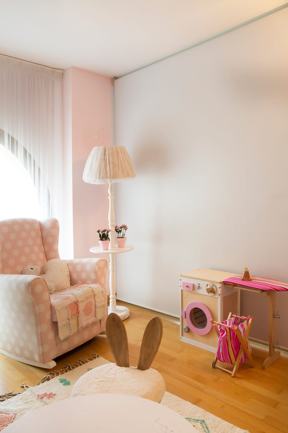 rincón de lectura con sillón mecedora de lunares blancos y fondo rosa