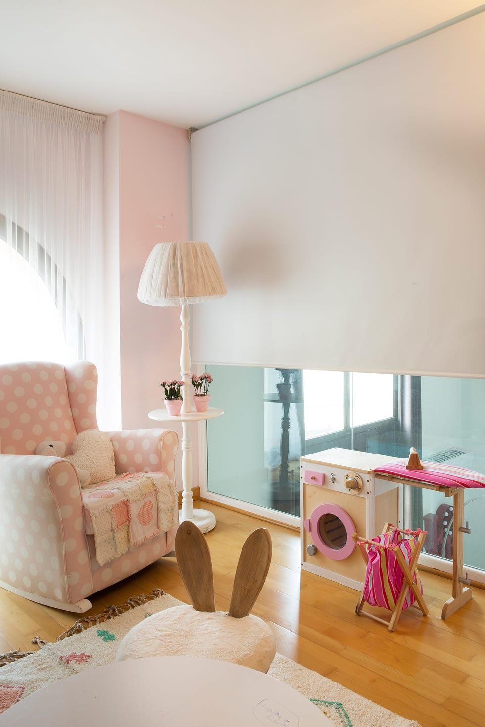 rincón de lectura con sillón mecedora de lunares blancos y fondo rosa, y screen