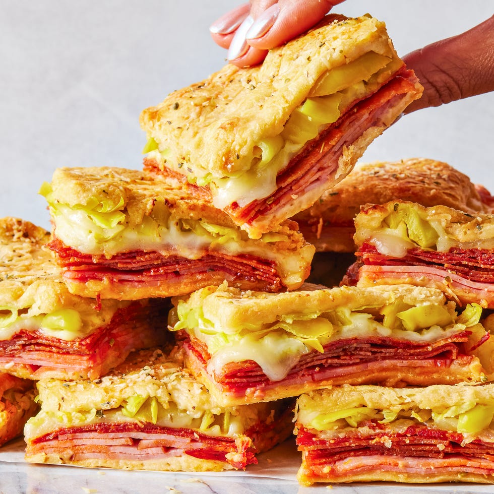 stacked sandwiches with layers of ham, pepperoni, cheese, and pepperoncinis between crescent dough