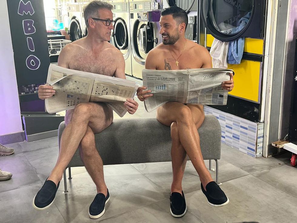 strictly come dancing stars anton du beke and giovanni pernice sitting on a bench with no clothes on and smiling at each other, with newspapers covering themselves