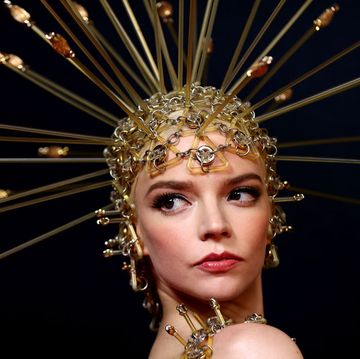 anya taylor joy wearing a gold dress and a headdress piece with embellishments sticking out