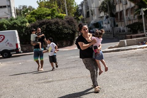 woman running with her children through the streets of ashdod