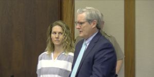 ruby franke wearing striped prison attire and looking over at an attorney during a court hearing