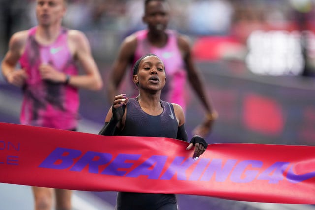 a runner breaks finishing tape reading breaking4 with a nike logo