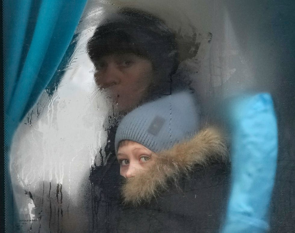 Een vrouw en een kind kijken donderdag uit het raam van een bus als ze Sievierodonetsk in het oosten van Oekrane verlaten Een oorlog in Oekrane kan leiden tot massale slachtoffers een vluchtelingencrisis en weergalmen over de hele wereld zeggen conflictexperts