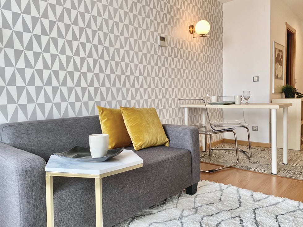 salón moderno con sofá gris, mesa auxiliar de mármol y papel pintado geométrico