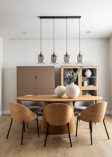 mesa de comedor ovalada de madera con sillas de madera a juego y lámpara suspendida