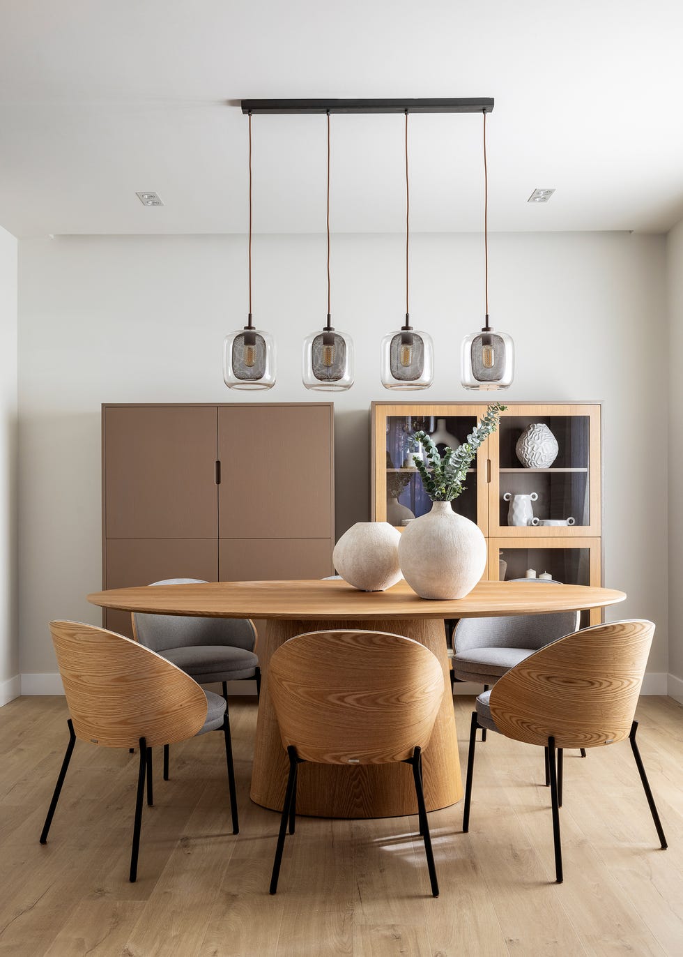 mesa de comedor ovalada de madera con sillas de madera a juego y lámpara suspendida