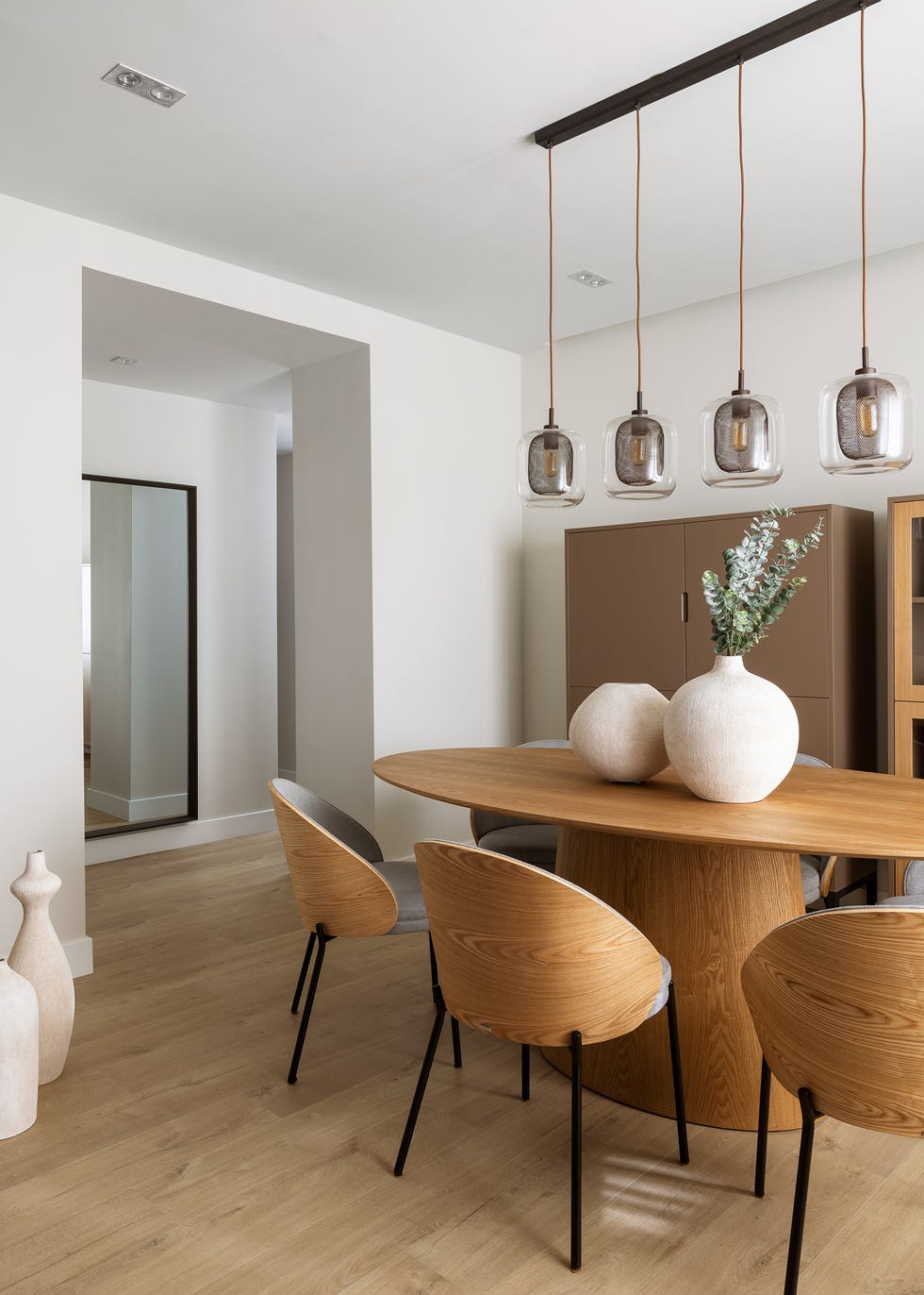 mesa de comedor ovalada de madera con sillas de madera a juego y lámpara suspendida