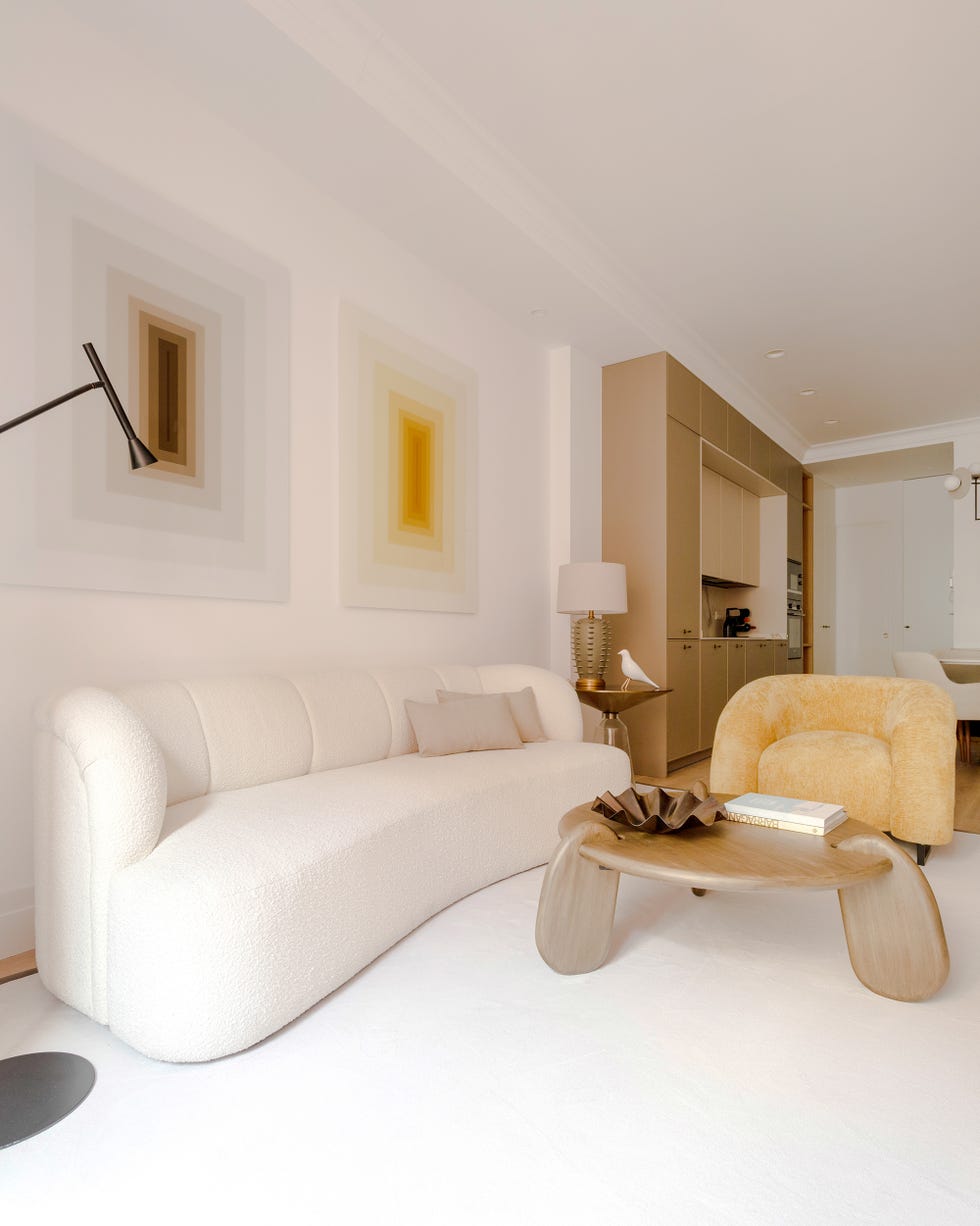 salón con sofá beige, butaca mostaza y mesa de centro de madera con forma orgánica