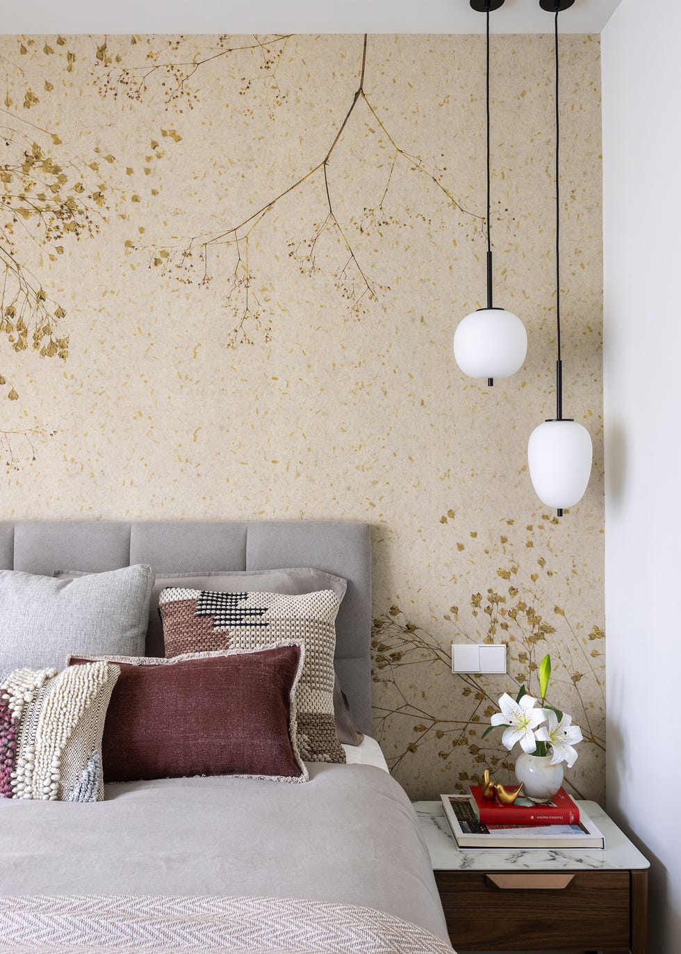 dormitorio con papel pintado floral y cabecero tapizado gris