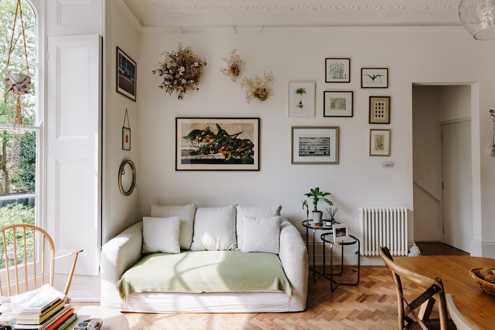 salón de estilo vintage con sofá blanco, parquet en espiga y cuadros en las paredes