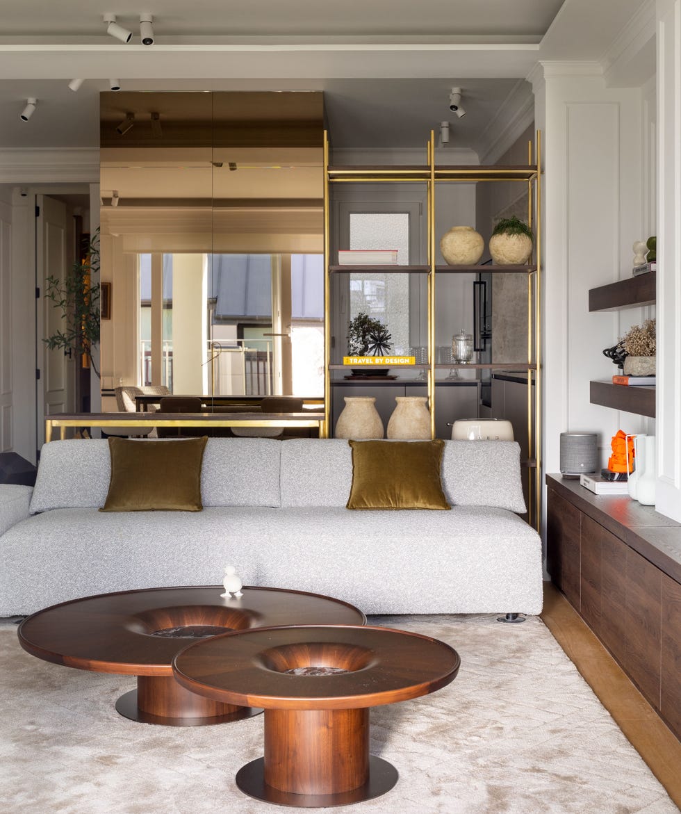 salón con sofá gris de diseño moderno y mesas de centro de madera redondas