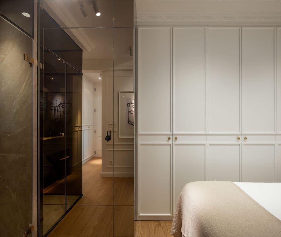 dormitorio con baño en suite y armario blanco empotrado con molduras decorativas