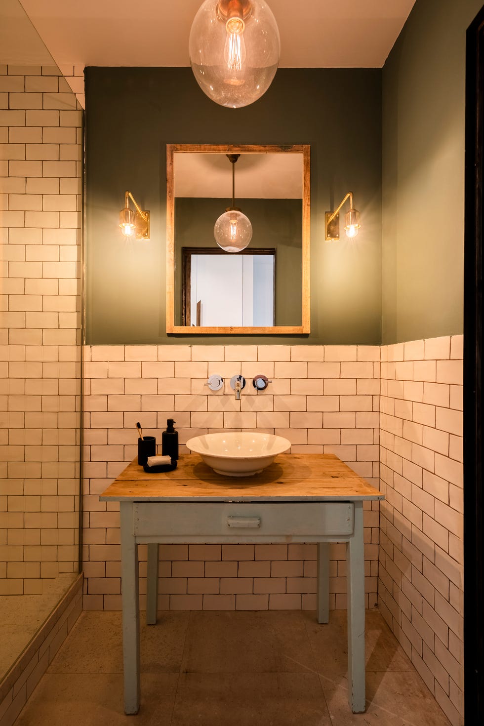 baño con ducha revestido con azules tipo metro blancos y mesa rústica de madera