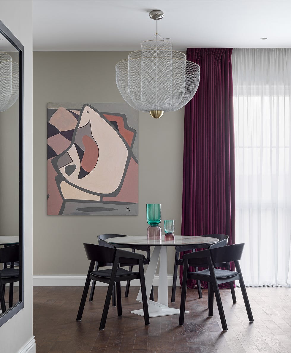 comedor de diseño moderno con mesa blanca redonda y cuadro abstracto en la pared