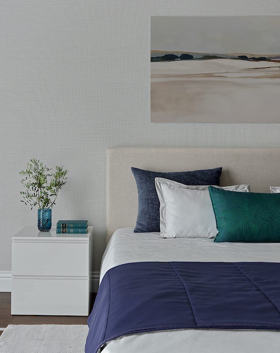 dormitorio con cabecero beige y mesita de noche blanca moderna