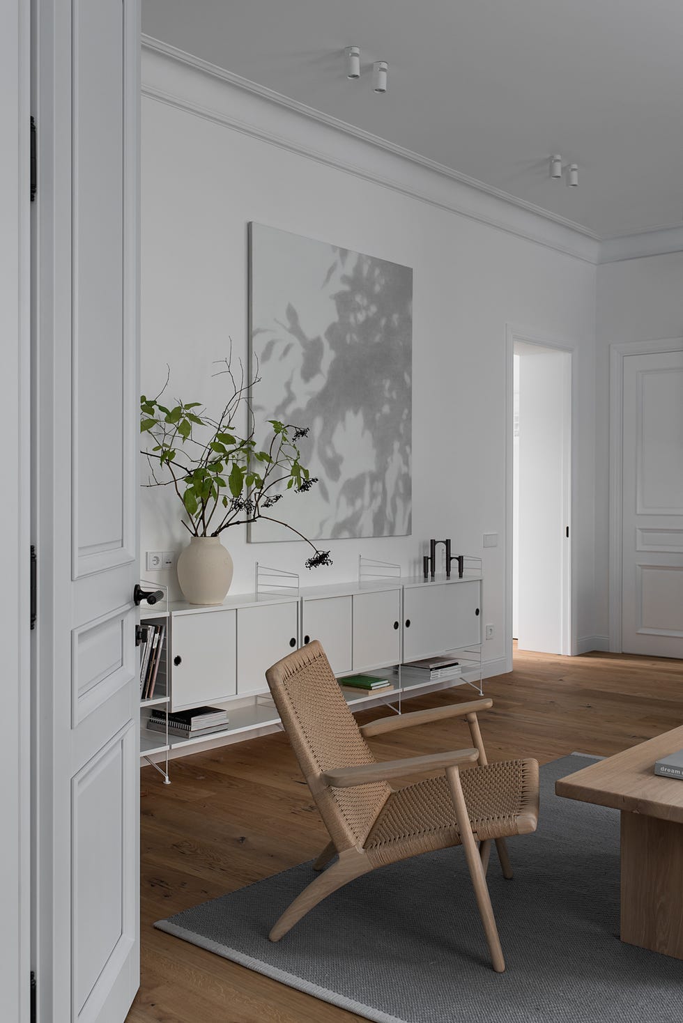 salón nórdico con butaca de ratán y estantería blanca