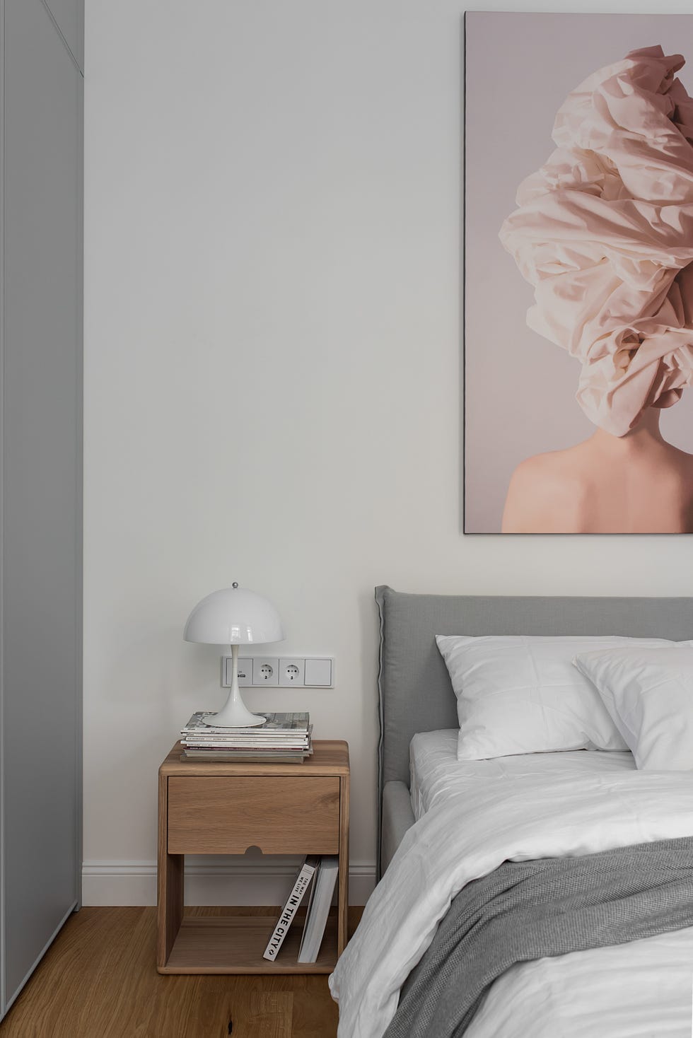 dormitorio nórdico decorado en gris con mesita madera y cuadro sobre la cama