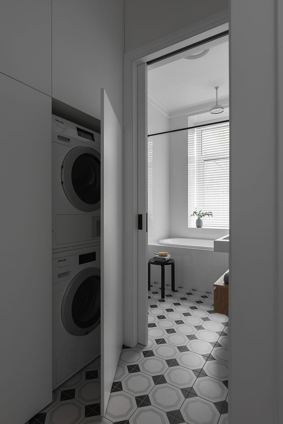 baño moderno con suelo de baldosas geométricas y espacio con lavadora y secadora