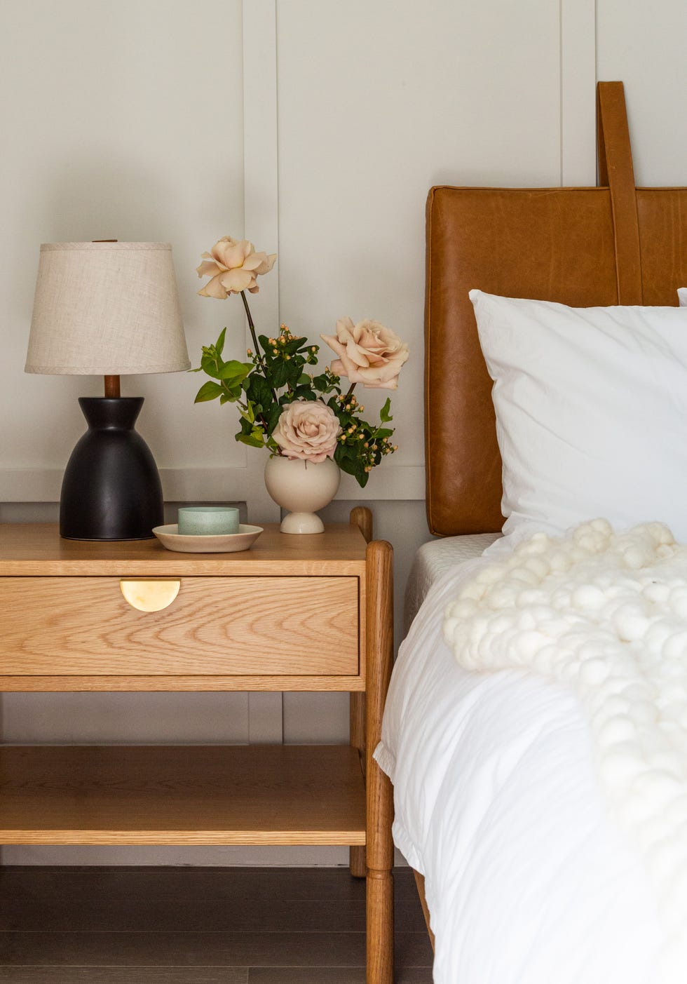 cama con cabecero de piel camel y mesita de noche de madera