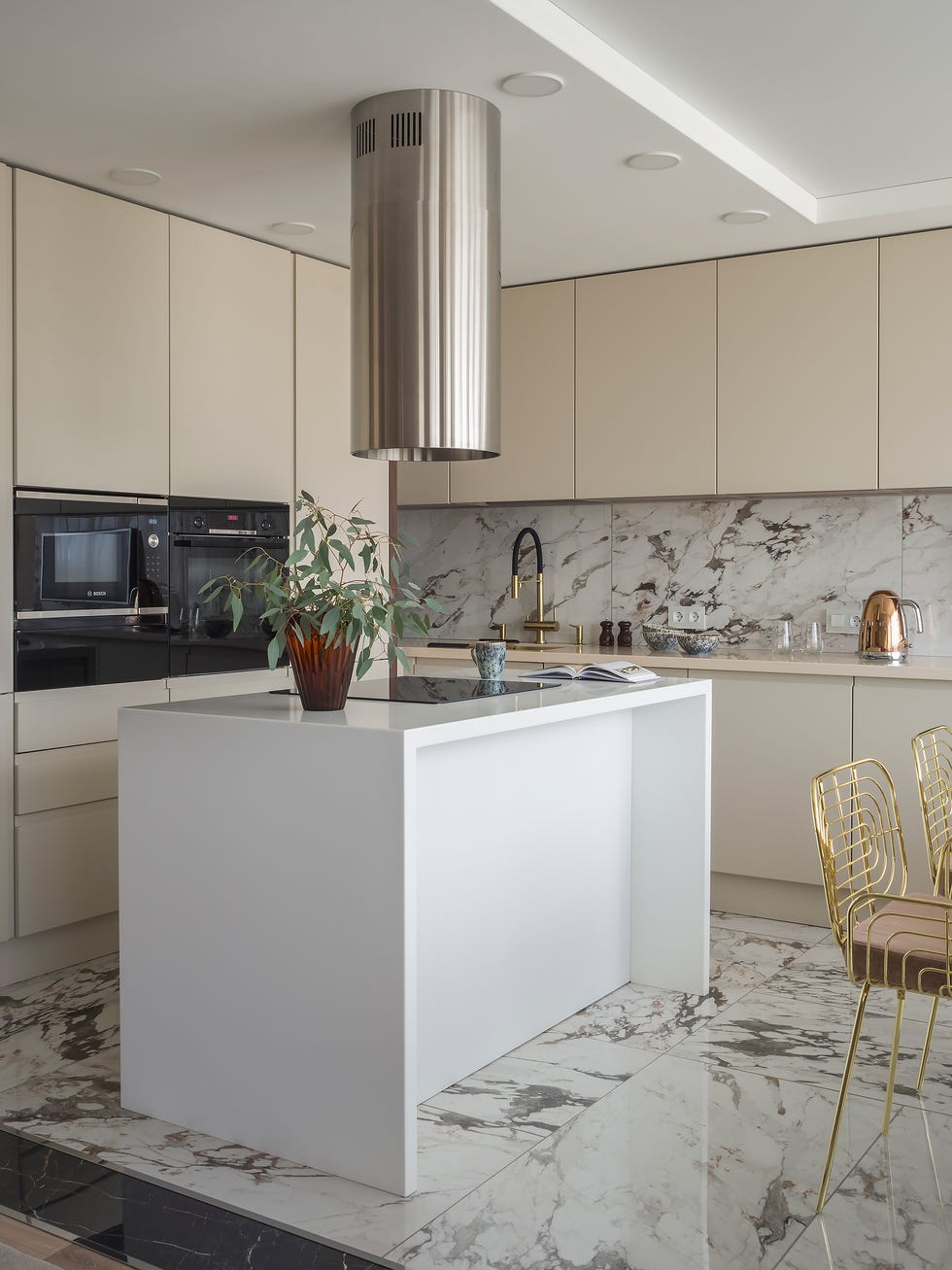 cocina con isla central blanca y suelo y frentes de mármol