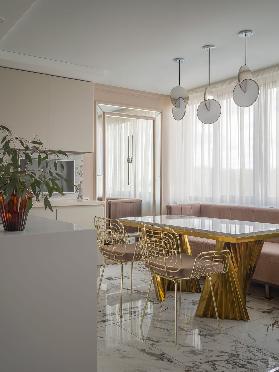 comedor con mesa de mármol y metal dorado, sillas doradas y banco de terciopelo rosa