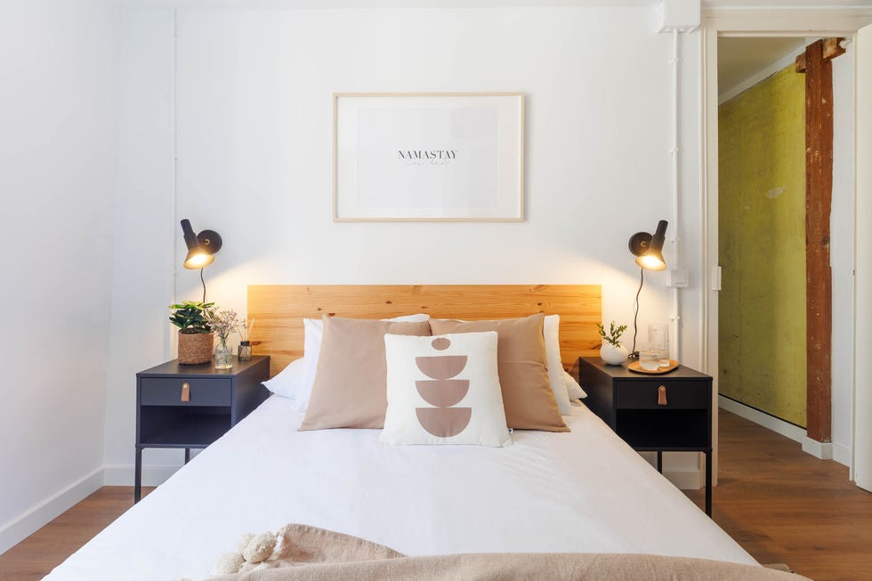 dormitorio con cama y cabecero de madera y mesitas negras