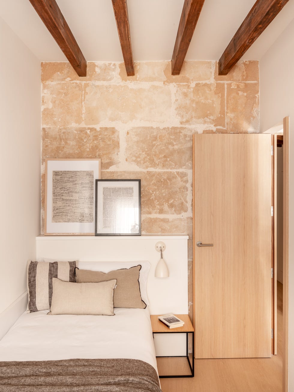 dormitorio con pared de piedra vista y techo con vigas de madera