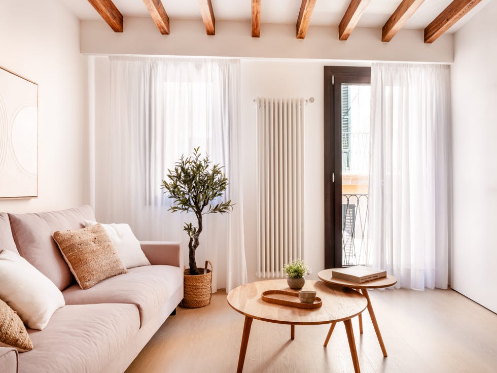 salón con sofá, mesas de madera tipo nido y techo con vigas de madera
