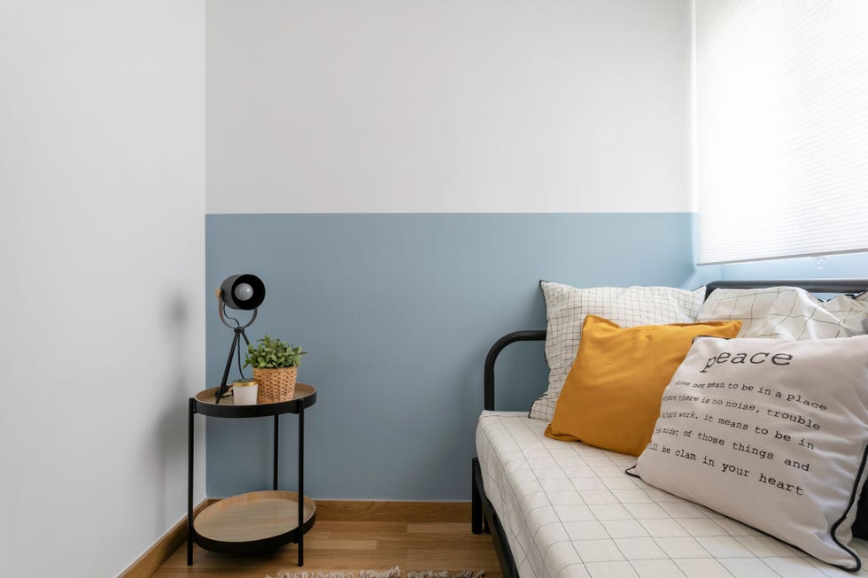 habitación de invitados con cama tipo nido con estructura metálica negra y pared pintada en blanco y azul