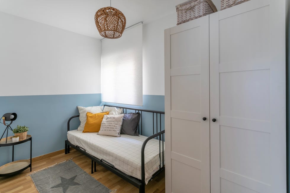 habitación de invitados con cama tipo nido con estructura metálica negra y pared pintada en blanco y azul