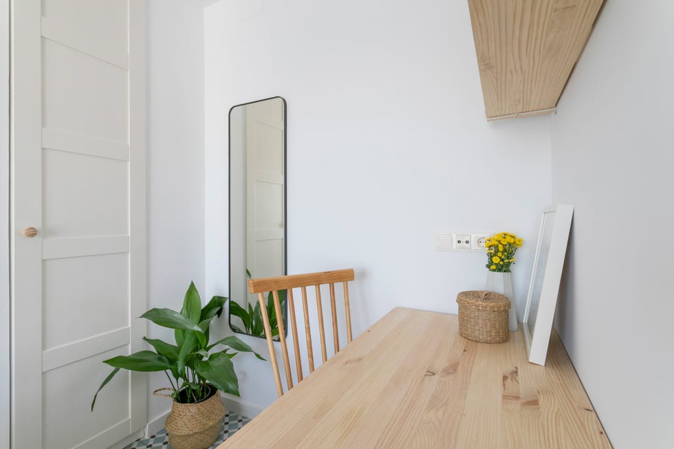 escritorio de diseño nórdico con baldas de madera y espejo de pared junto a cesta de fibras