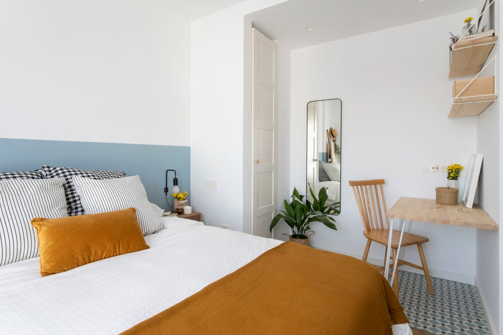 dormitorio de estilo mediterráneo decorado en blanco y azul con una pequeña mesa de escritorio de madera