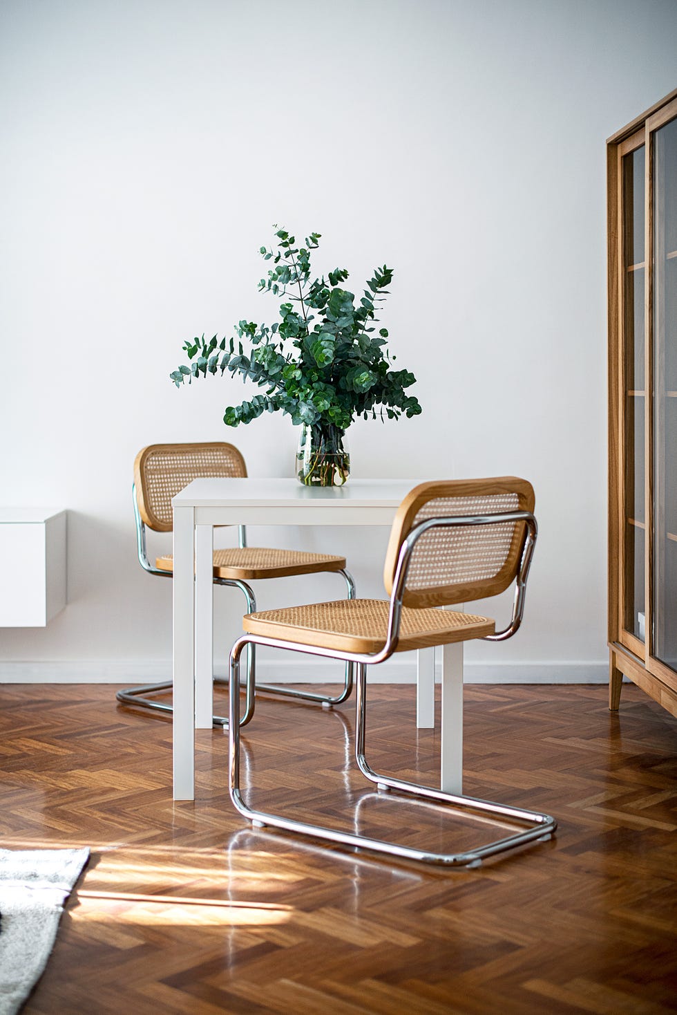 mesa blanca de comedor, sillas cesca y vitrina de madera