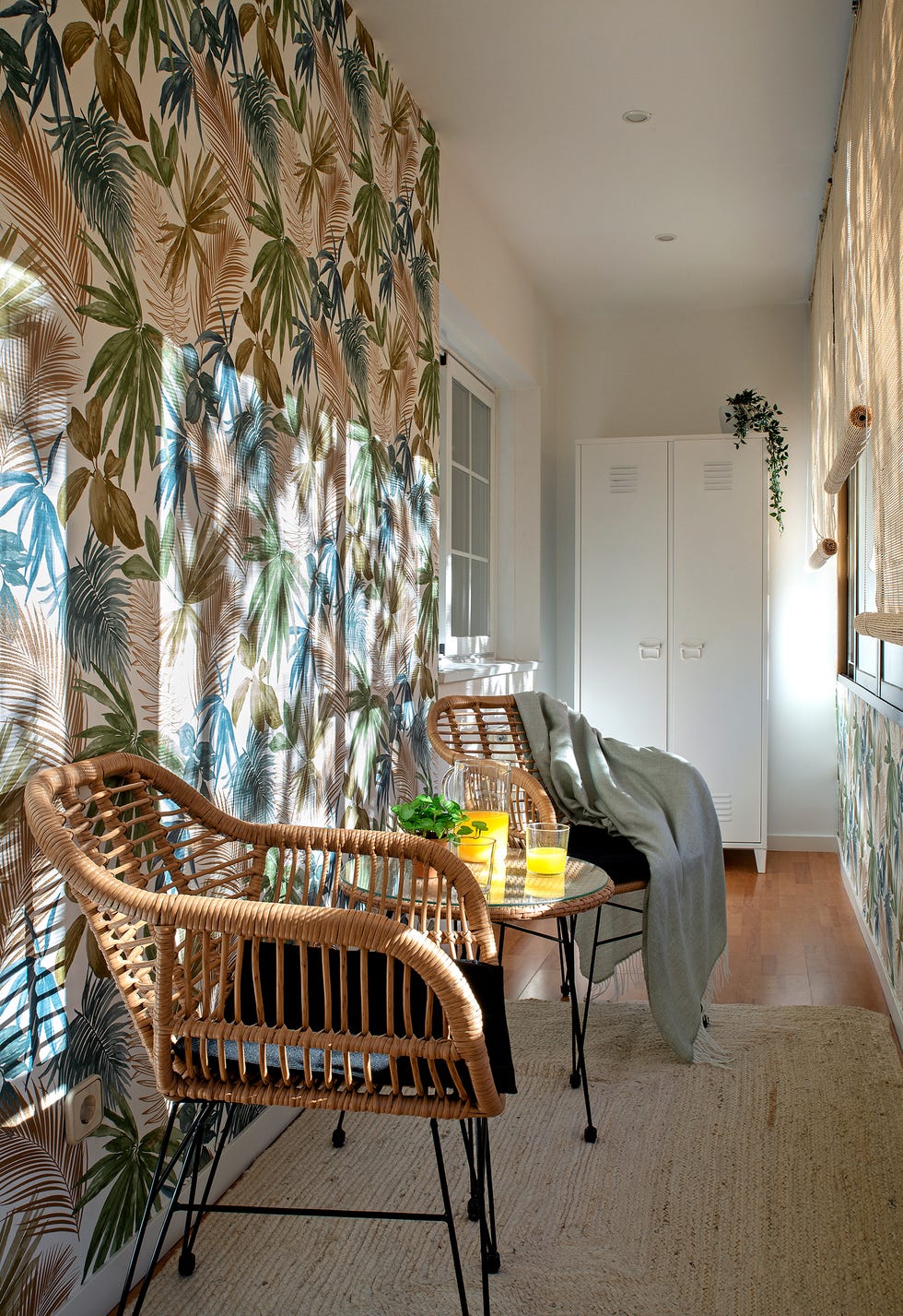 galería con papel pintado botánico y conjunto de sillas con mesa de ratán