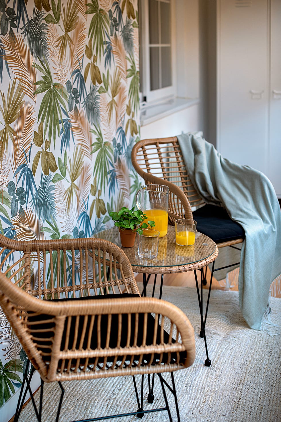 galería con papel pintado botánico y conjunto de sillas con mesa de ratán