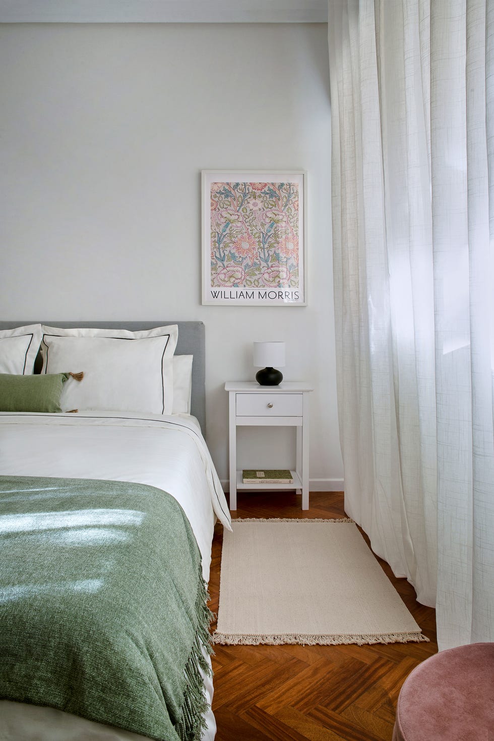 cama tapizada en gris y mesita de noche blanca