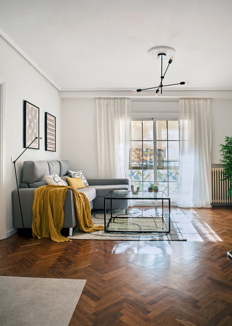 salón moderno con sofá gris con chaise longue y mesa de centro de metal negro y cristal