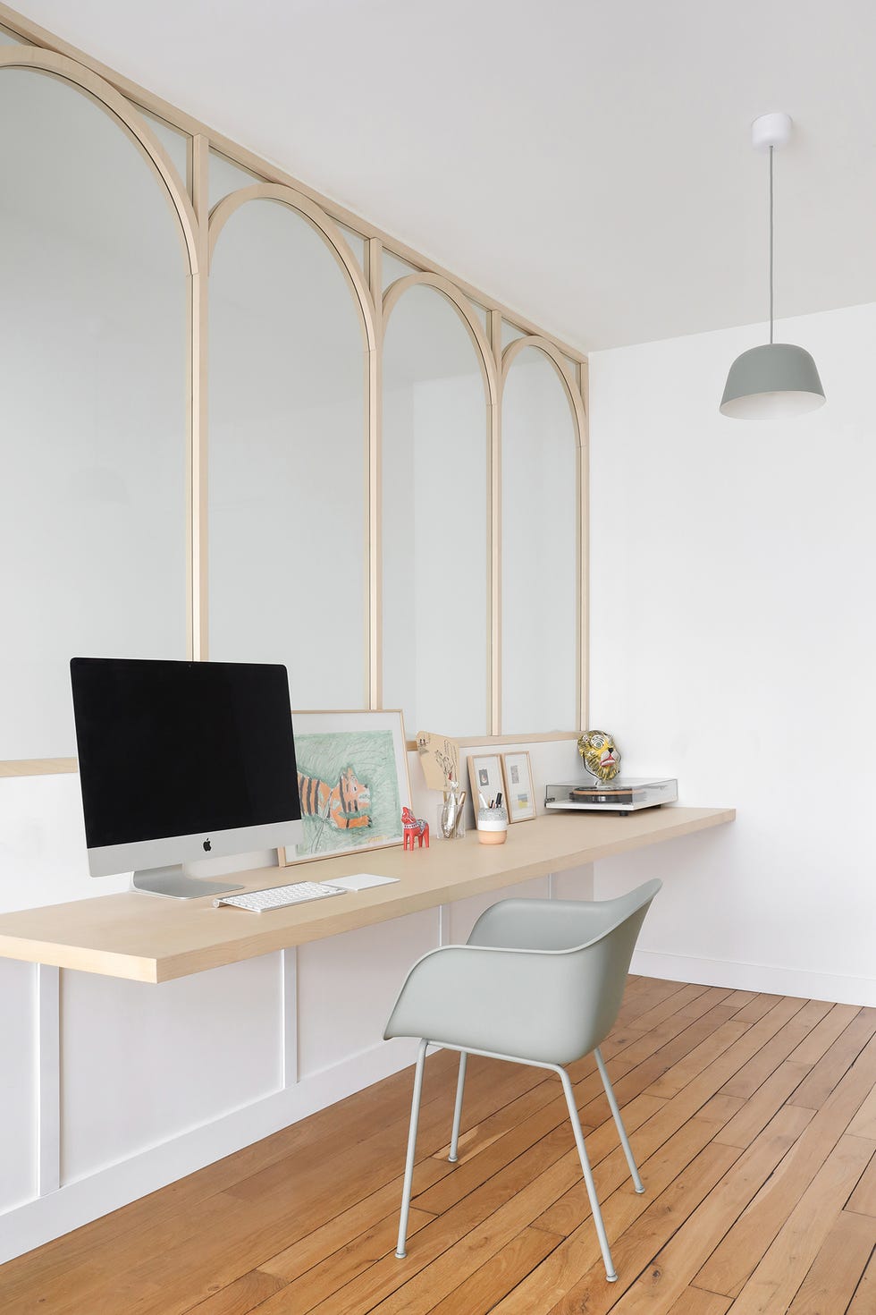 escritorio de estilo scandi con balda de madera flotante, silla gris y pared con molduras