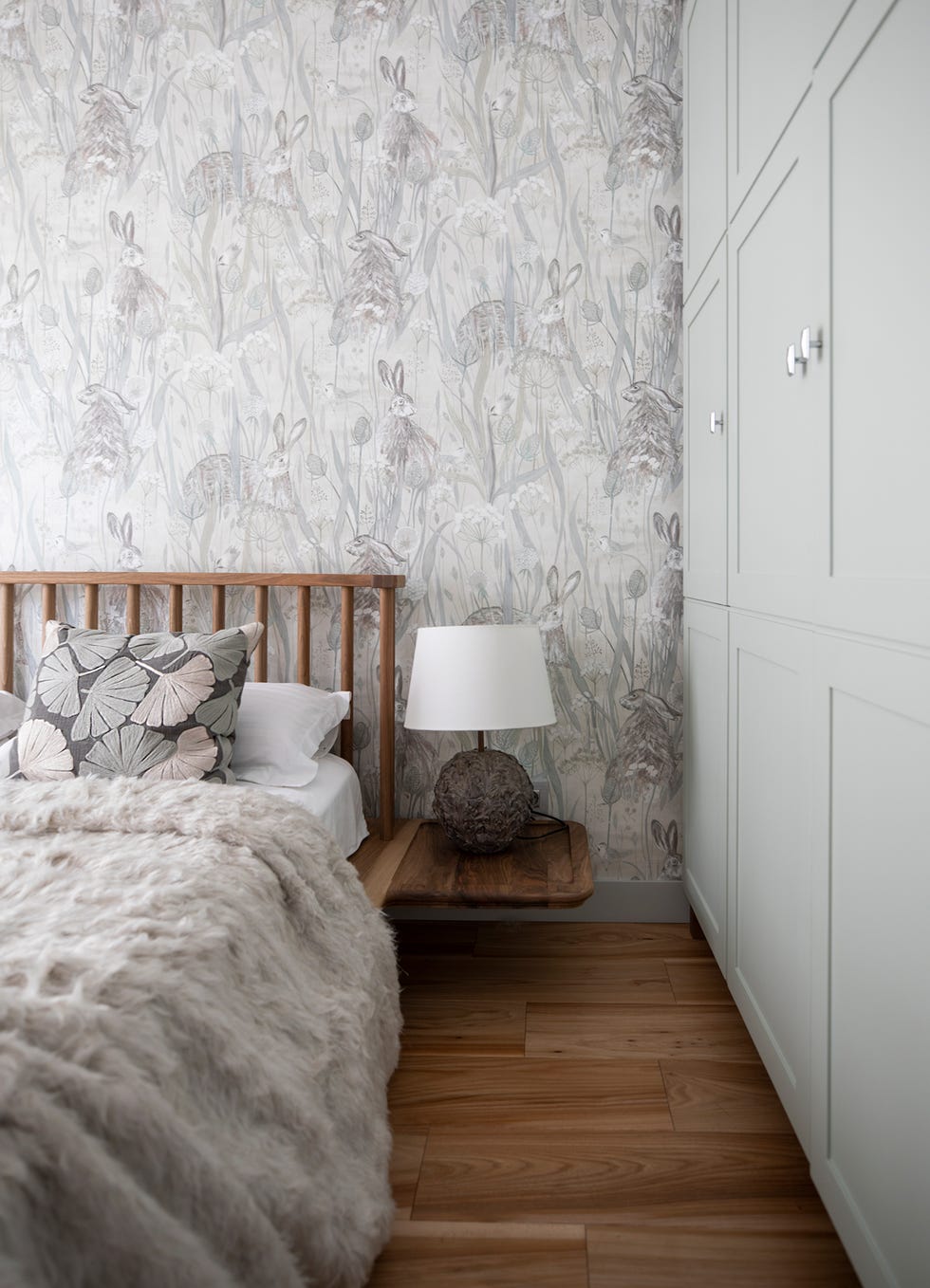 Dormitorio con cama de madera, papel pintado con motivos grises, y armario pintado en verde empolvado