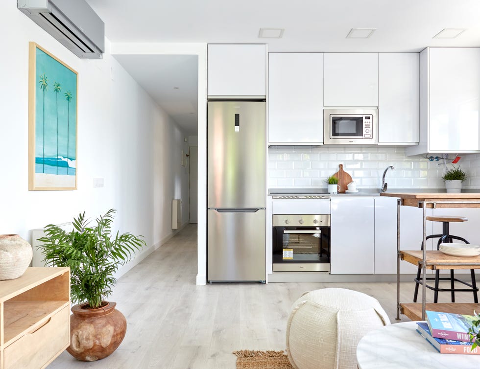cocina abierta diseñada en color blanco con barra de madera tipo industrial