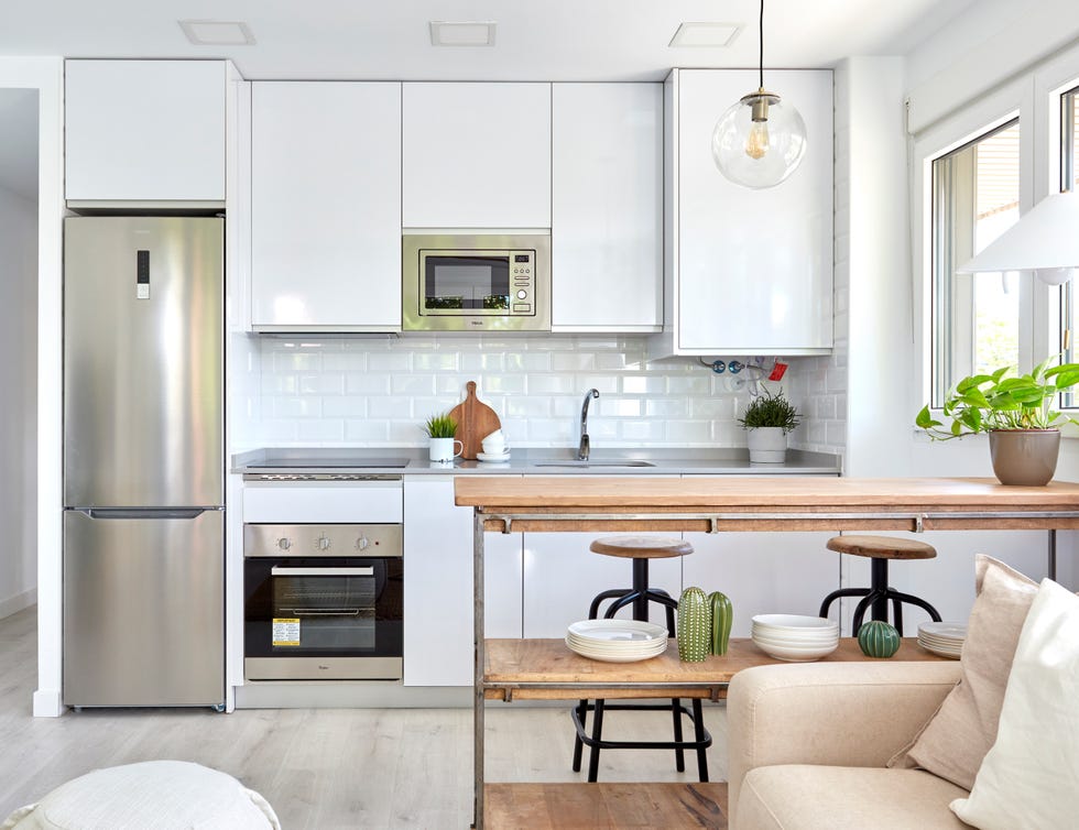 cocina abierta diseñada en color blanco con barra de madera tipo industrial