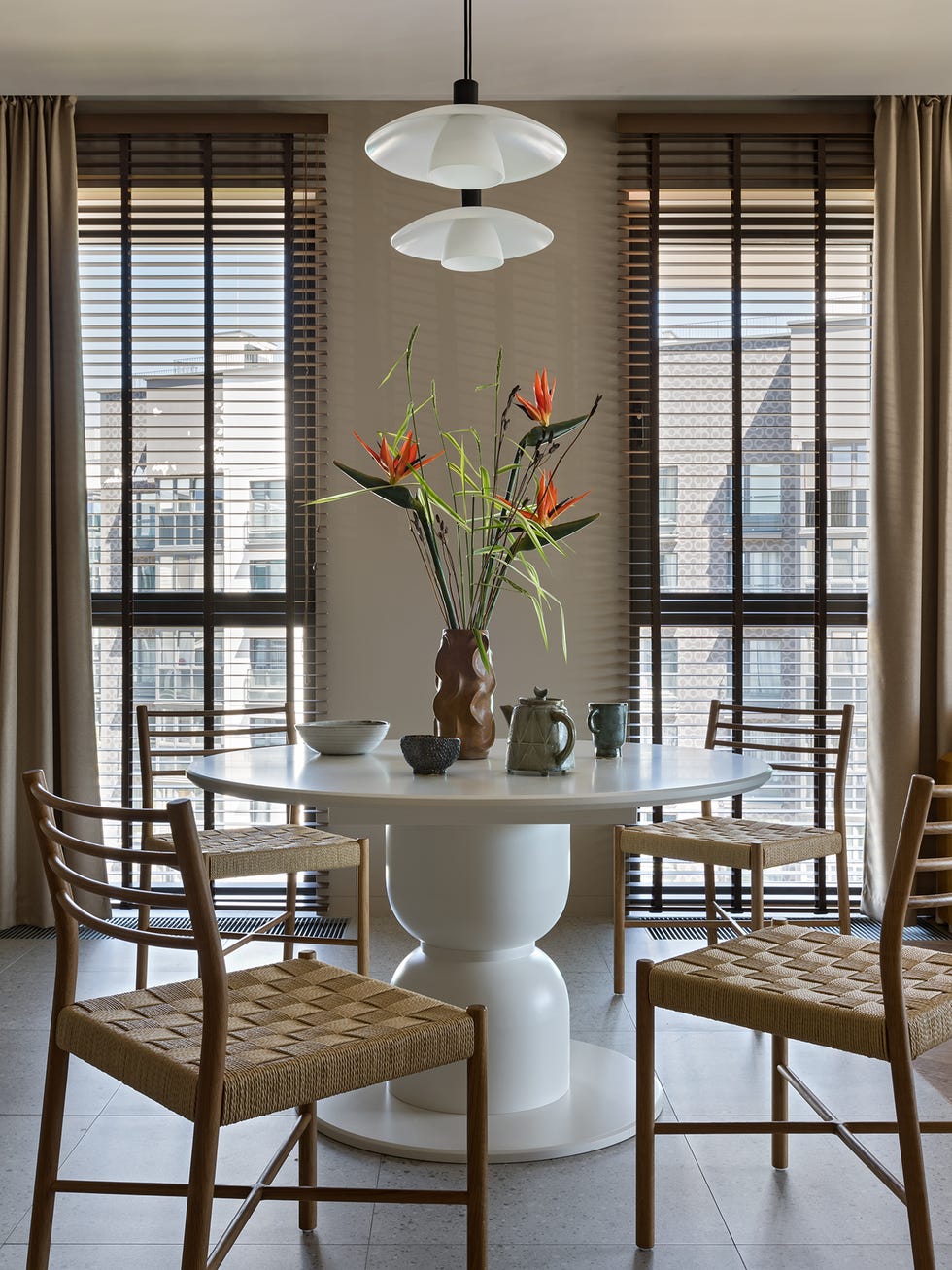 mesa de comedor redonda blanca y sillas con asiento de fibras y estructura de madera