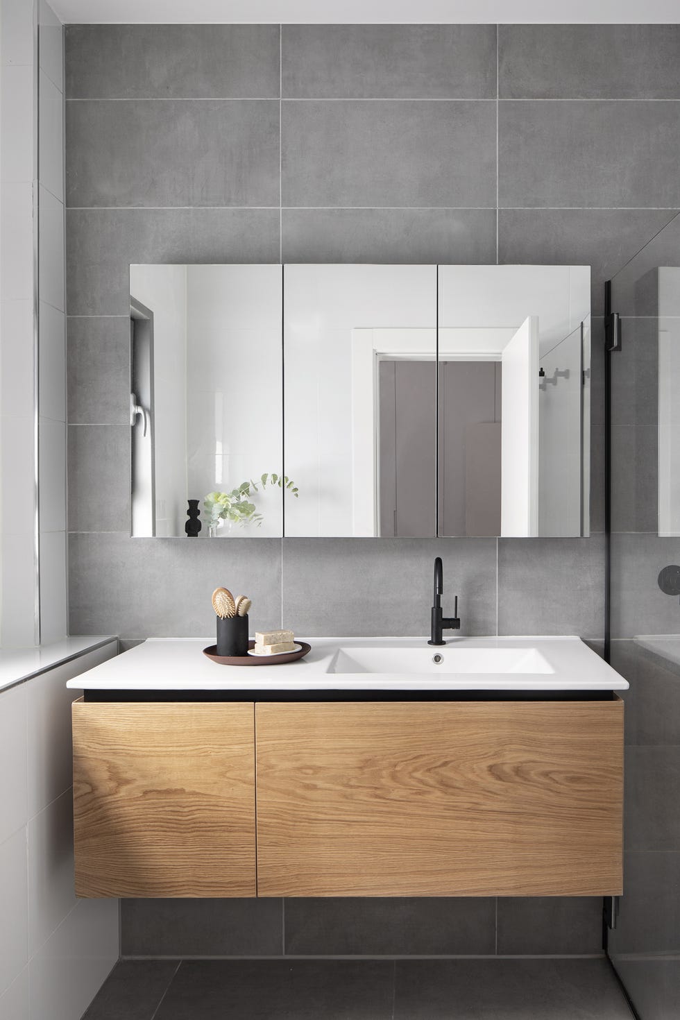 baño revestido con baldosas de cemento gris y mueble suspendido de madera