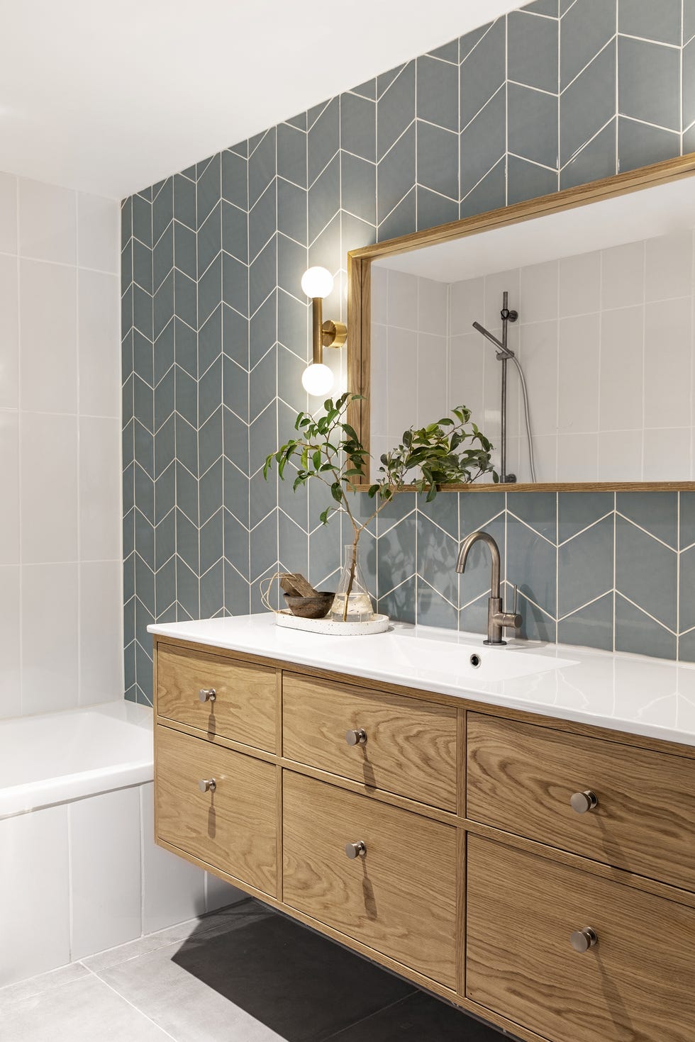 baño con mueble suspendido de madera y azulejos en espiga en color celeste